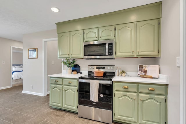 kitchen with stainless steel appliances, baseboards, green cabinets, and light countertops