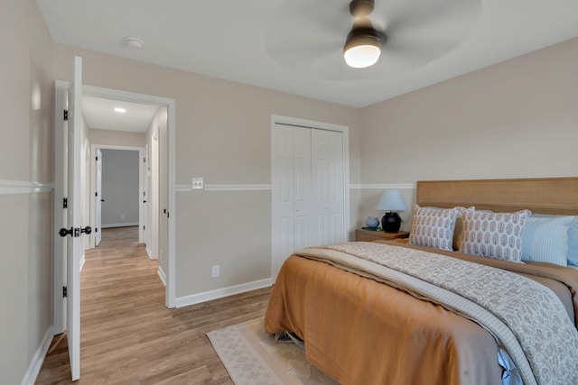 bedroom featuring a ceiling fan, a closet, light wood-style flooring, and baseboards