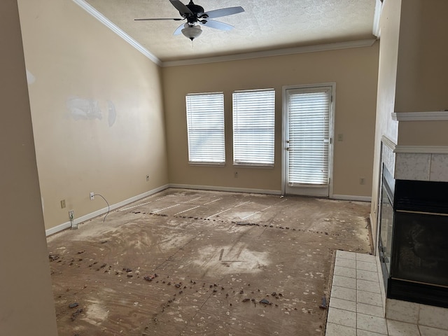 unfurnished living room featuring baseboards, a ceiling fan, a tiled fireplace, ornamental molding, and a textured ceiling