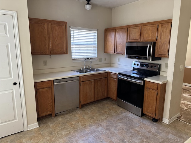 kitchen featuring appliances with stainless steel finishes, light countertops, brown cabinets, and a sink