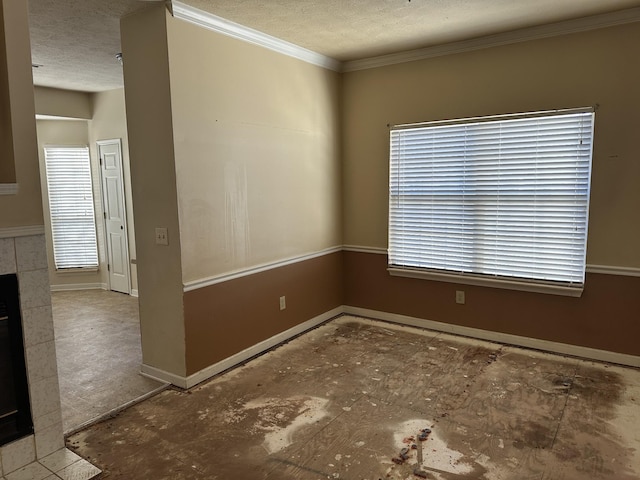 spare room featuring a textured ceiling, ornamental molding, and a fireplace