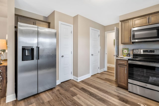 kitchen featuring appliances with stainless steel finishes, baseboards, and wood finished floors