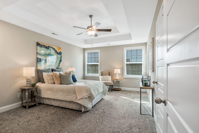 bedroom with visible vents, baseboards, a ceiling fan, a tray ceiling, and carpet floors