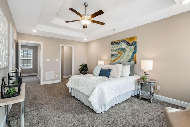 carpeted bedroom with visible vents, baseboards, a raised ceiling, and a ceiling fan