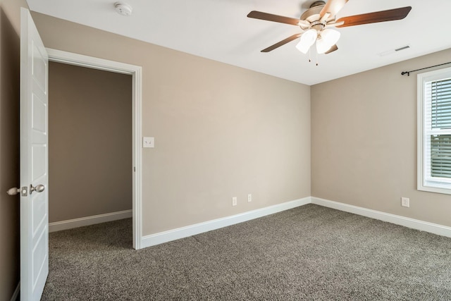 carpeted spare room featuring a ceiling fan, visible vents, and baseboards