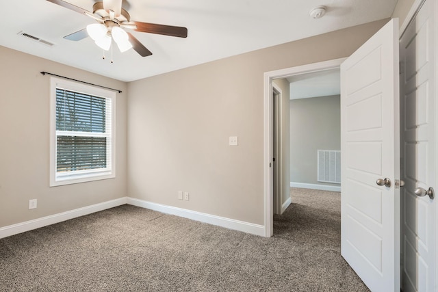 unfurnished bedroom with a ceiling fan, dark carpet, visible vents, and baseboards