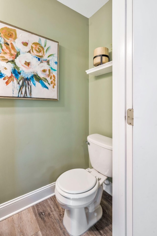 bathroom with baseboards, toilet, and wood finished floors