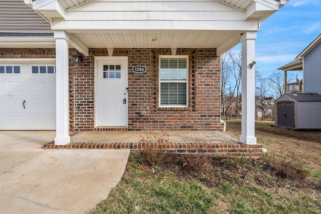 doorway to property with concrete driveway, brick siding, a porch, and an attached garage