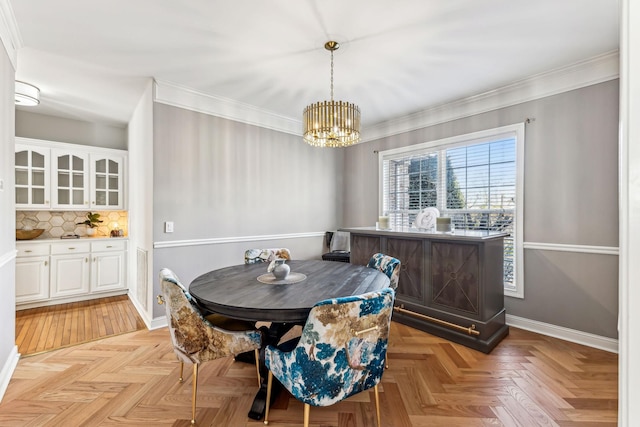 dining area featuring a notable chandelier, crown molding, and baseboards