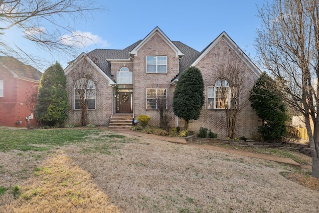 traditional home featuring a front yard and brick siding