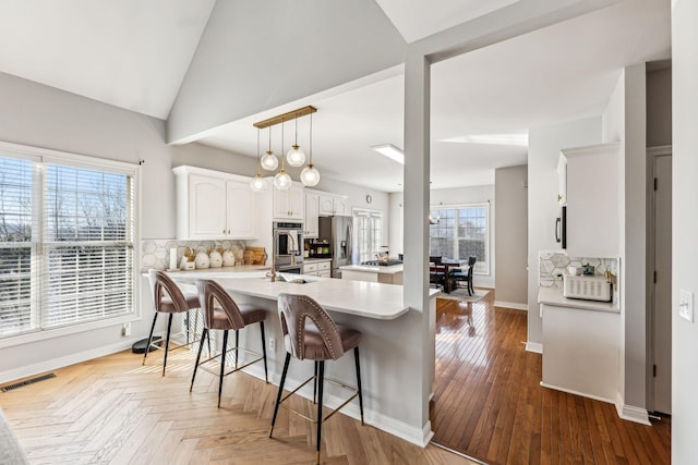 kitchen featuring tasteful backsplash, visible vents, a breakfast bar area, a peninsula, and stainless steel appliances