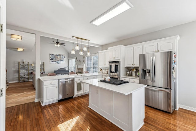 kitchen with appliances with stainless steel finishes, lofted ceiling, and white cabinets