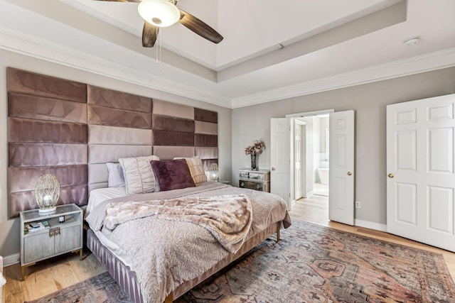 bedroom with baseboards, a raised ceiling, ceiling fan, ornamental molding, and wood finished floors