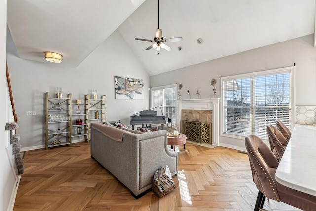 living area with high vaulted ceiling, a premium fireplace, a ceiling fan, and baseboards