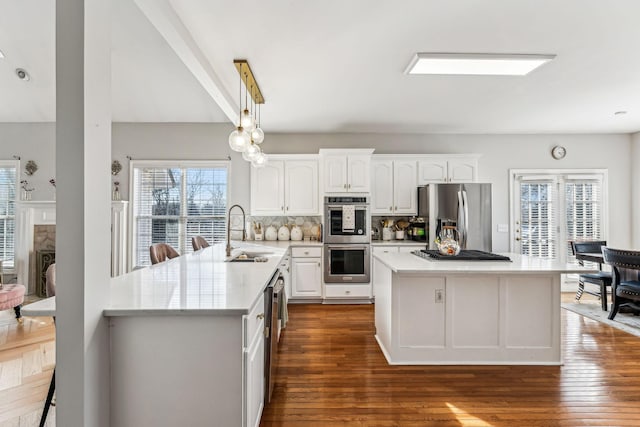 kitchen with stainless steel appliances, light countertops, white cabinetry, and a sink