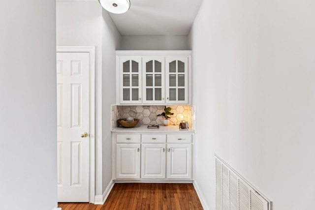 bar with baseboards, dark wood-style flooring, visible vents, and decorative backsplash