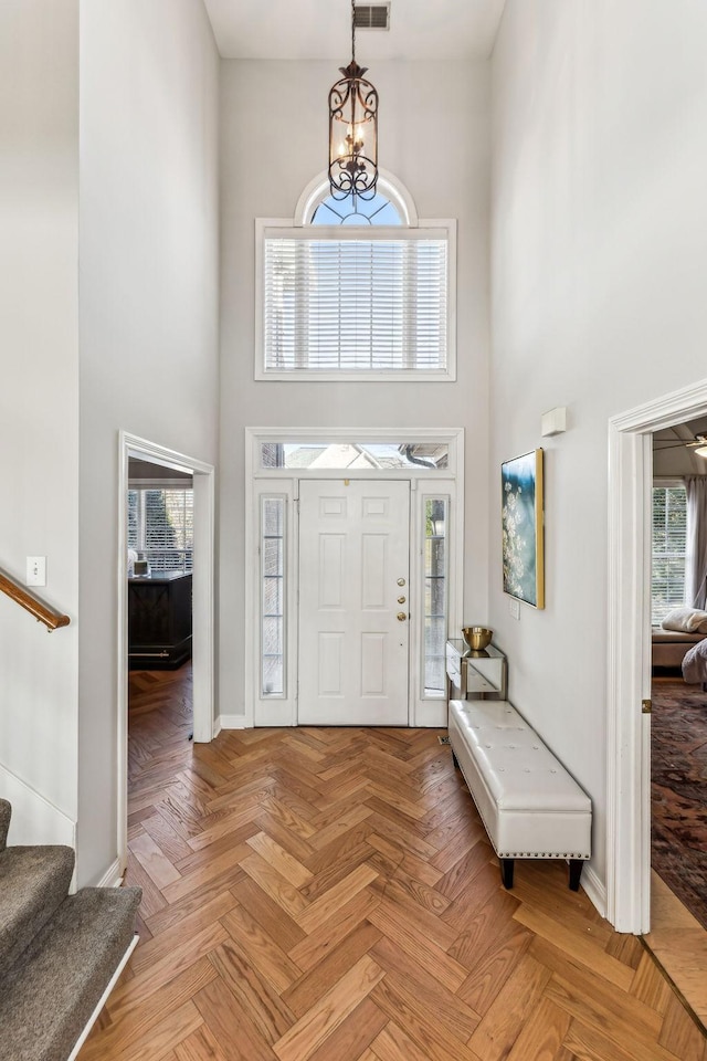 entryway with baseboards, stairway, a towering ceiling, and an inviting chandelier