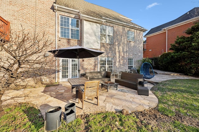 back of property with an outdoor living space with a fire pit, a patio, and brick siding