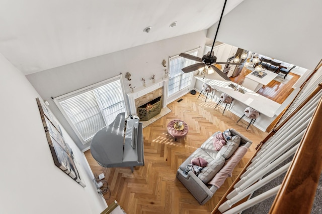 living area with a high end fireplace, ceiling fan, and lofted ceiling