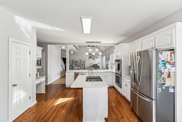 kitchen featuring dark wood finished floors, light countertops, appliances with stainless steel finishes, white cabinets, and a peninsula