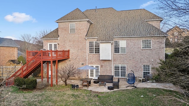 rear view of house featuring a deck, brick siding, stairs, a yard, and a patio area