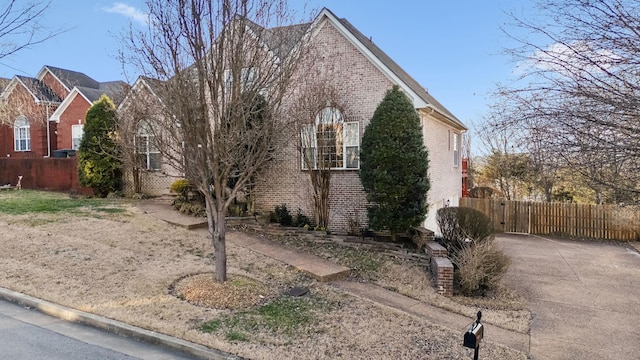 view of side of property featuring brick siding and fence