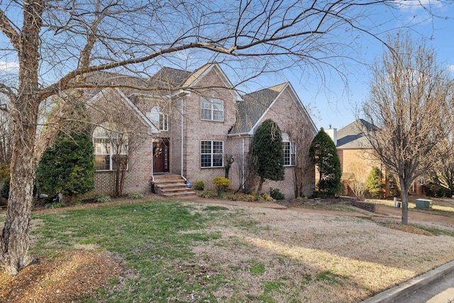 traditional-style house featuring a front lawn and brick siding