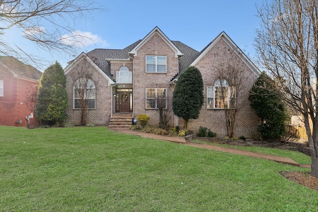 traditional home with brick siding, a shingled roof, a front yard, and fence