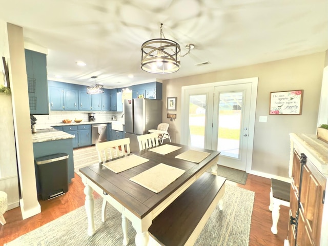 dining room with dark wood-type flooring, visible vents, baseboards, and an inviting chandelier