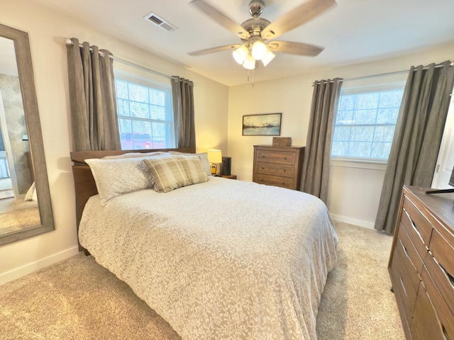 bedroom featuring light colored carpet, visible vents, baseboards, and multiple windows