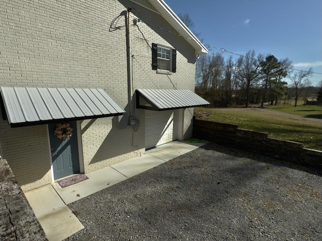 view of side of home featuring a garage, driveway, and brick siding