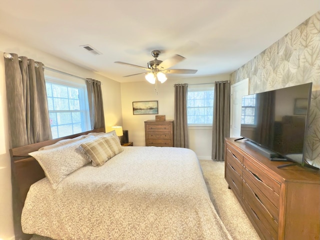 bedroom with visible vents, multiple windows, ceiling fan, and light carpet