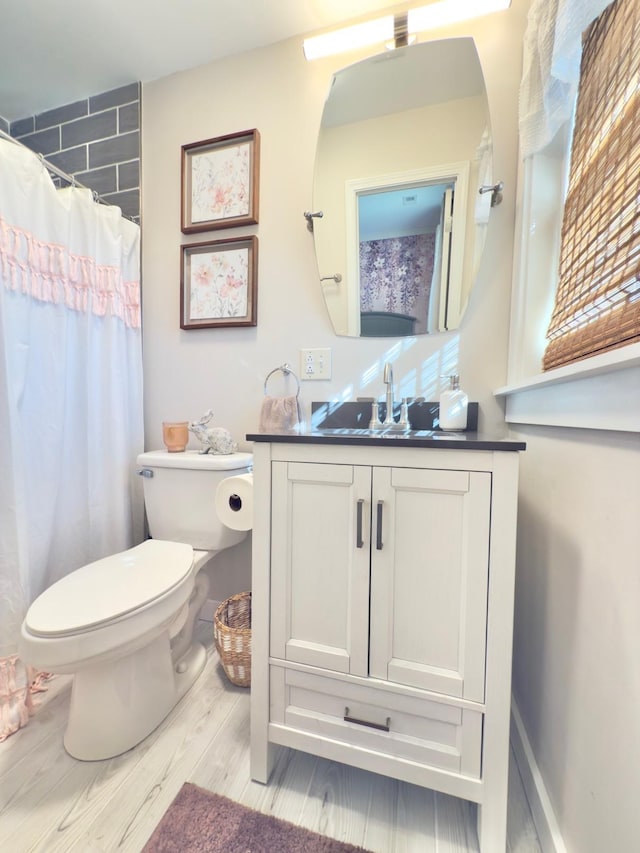 full bath with toilet, a shower with curtain, wood finished floors, and vanity