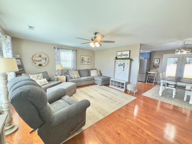 living room featuring a ceiling fan, visible vents, and wood finished floors