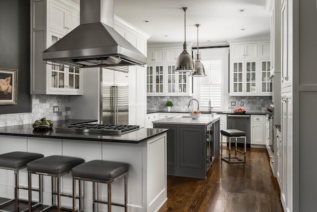 kitchen featuring dark wood-style floors, island exhaust hood, a breakfast bar area, white cabinetry, and a peninsula