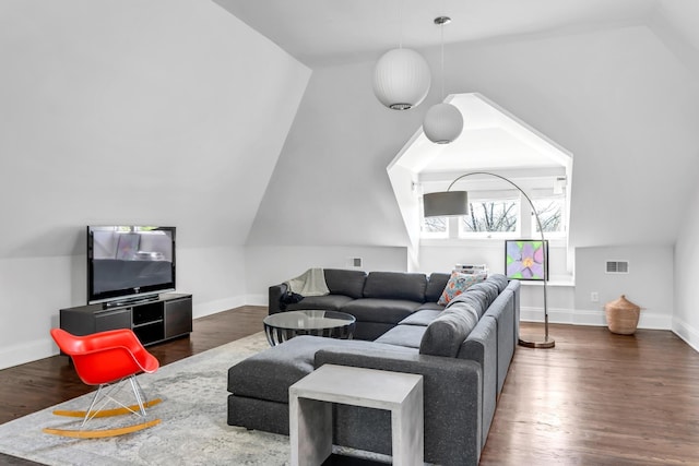 living area with baseboards, visible vents, vaulted ceiling, and wood finished floors