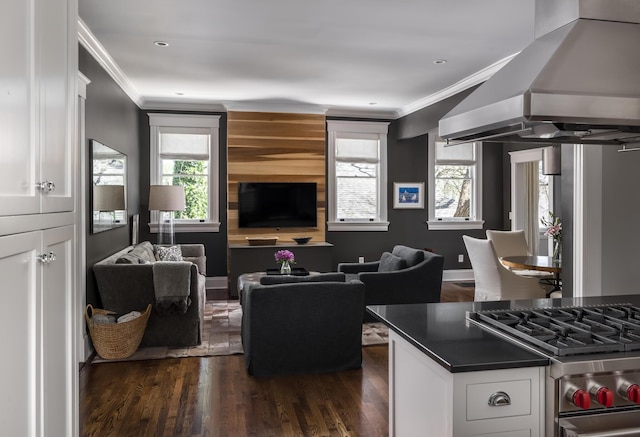 kitchen featuring crown molding, dark countertops, gas stove, white cabinetry, and wall chimney exhaust hood