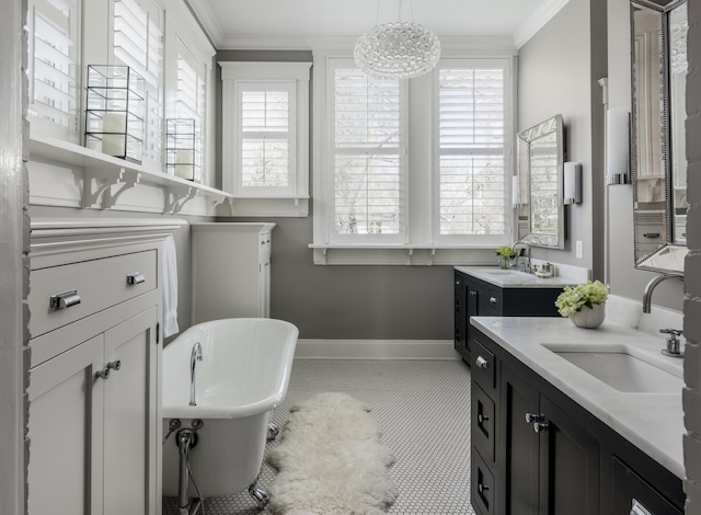 bathroom featuring ornamental molding, a freestanding tub, a sink, and baseboards