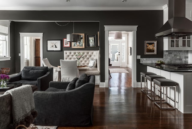 living area with dark wood finished floors, crown molding, and baseboards