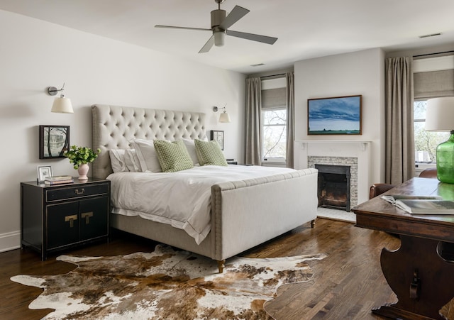 bedroom featuring ceiling fan, dark wood-type flooring, a fireplace with flush hearth, and baseboards