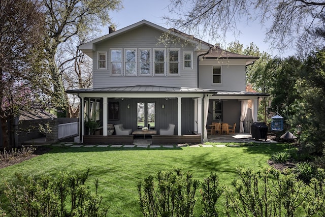 back of house featuring a standing seam roof, a yard, and metal roof