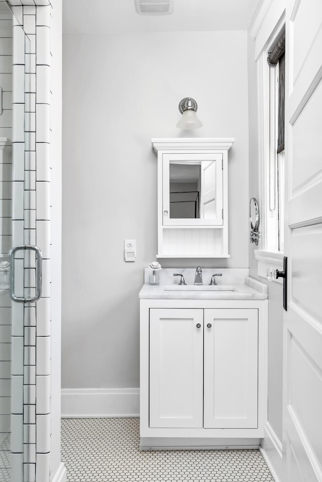 full bath featuring vanity, baseboards, and an enclosed shower