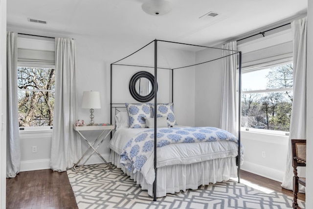 bedroom with baseboards, visible vents, and wood finished floors