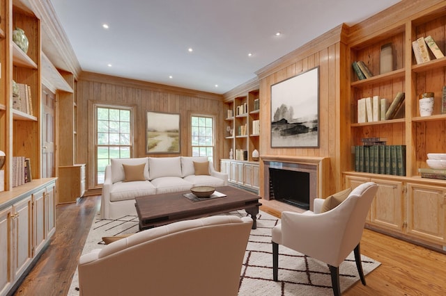 living room with light wood-type flooring, a fireplace with raised hearth, crown molding, and wooden walls