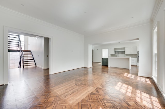 unfurnished living room featuring ornamental molding, baseboards, and stairs