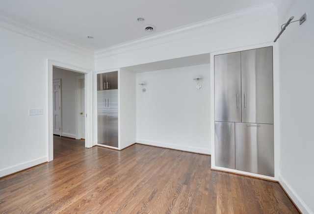 spare room featuring baseboards, wood finished floors, and crown molding