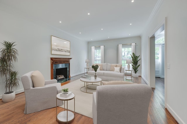 living area with crown molding, recessed lighting, a high end fireplace, wood finished floors, and baseboards