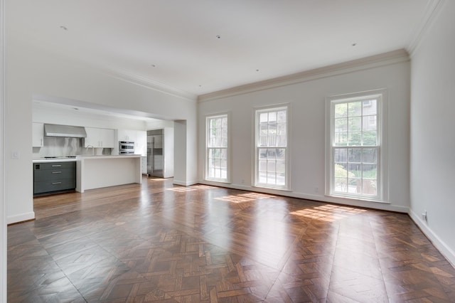 unfurnished living room featuring a sink, crown molding, and baseboards