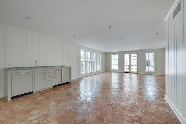 unfurnished living room with a wealth of natural light, visible vents, and a sink