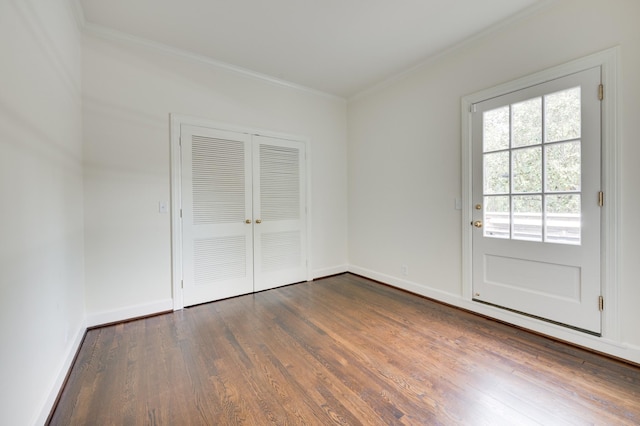 interior space with crown molding, a closet, baseboards, and wood finished floors